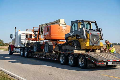 Secure transport of manlifts and skid steers on a trailer.